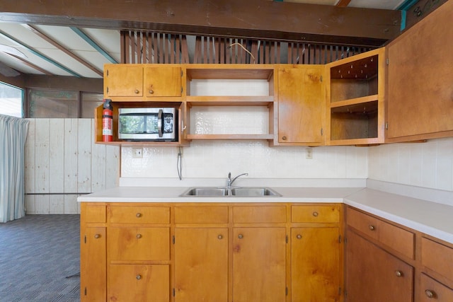 kitchen with stainless steel microwave, light countertops, open shelves, and a sink