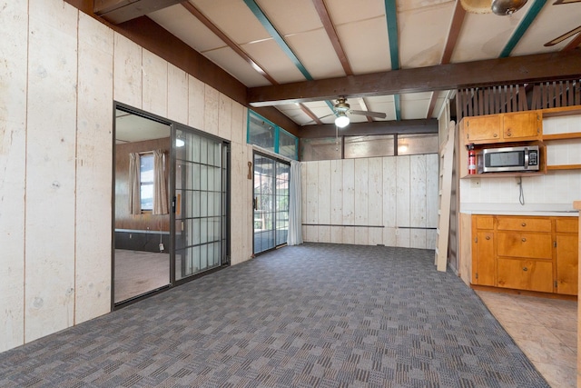 interior space featuring wood walls, a ceiling fan, and beamed ceiling