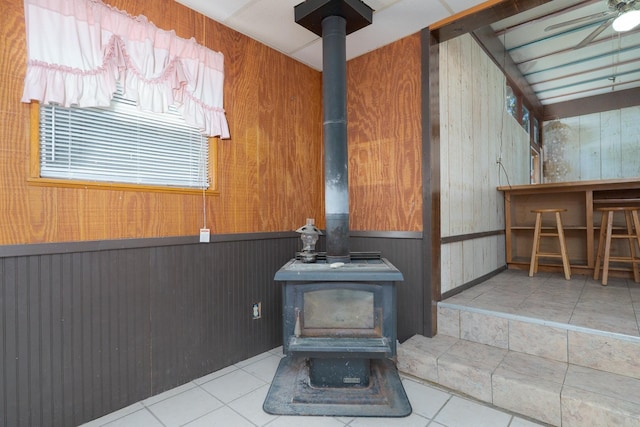room details featuring wood walls, a wood stove, and a wainscoted wall