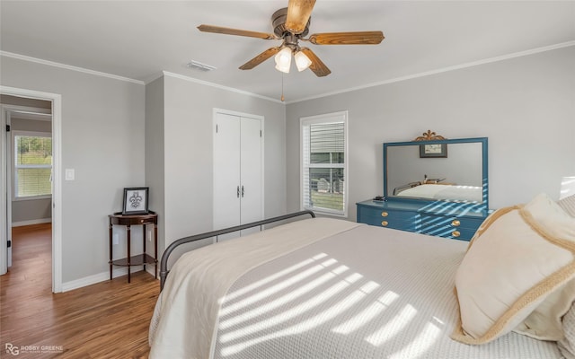 bedroom featuring visible vents, baseboards, a ceiling fan, wood finished floors, and crown molding
