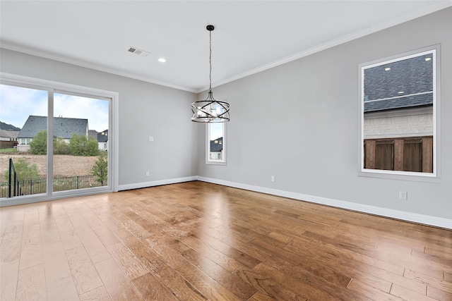 empty room featuring baseboards, visible vents, a chandelier, crown molding, and hardwood / wood-style floors