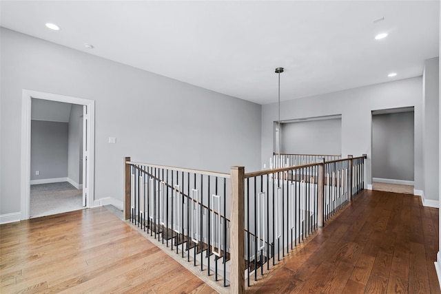 corridor featuring recessed lighting, hardwood / wood-style floors, baseboards, and an upstairs landing