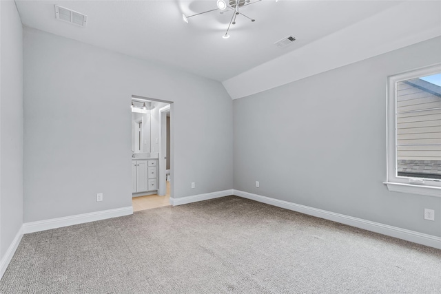 carpeted empty room with baseboards, lofted ceiling, and visible vents