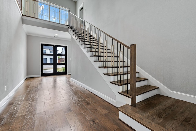 entryway with stairway, a high ceiling, wood finished floors, and baseboards