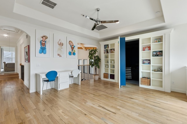 1501 Latigo Ct, Prosper, TX 75078 - interior space featuring a ceiling fan, a tray ceiling, light wood finished floors, arched walkways, and baseboards
