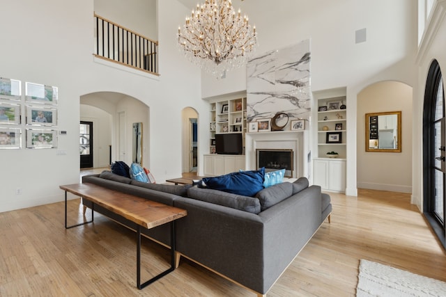 1501 Latigo Ct, Prosper, TX 75078 - living area with built in shelves, a towering ceiling, arched walkways, light wood-type flooring, and baseboards