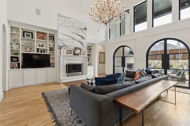 1501 Latigo Ct, Prosper, TX 75078 - living room with a towering ceiling, arched walkways, built in features, a fireplace, and light wood finished floors