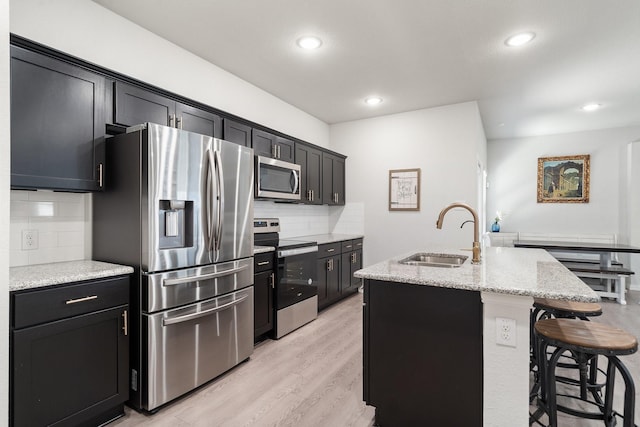 4652 Raleigh Dalton Rd, Dallas, TX 75227 - kitchen featuring stainless steel appliances, a kitchen island with sink, a sink, backsplash, and dark cabinets