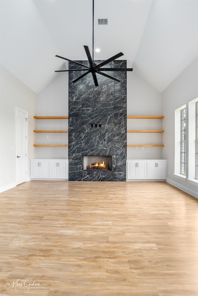 unfurnished living room with high vaulted ceiling, light wood-style floors, a fireplace, baseboards, and visible vents