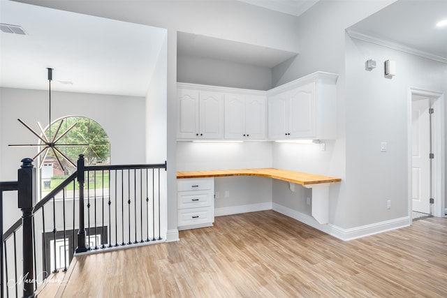 interior space with visible vents, light wood-style flooring, built in desk, and ornamental molding