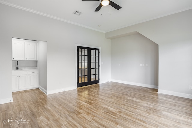 interior space with a ceiling fan, a sink, light wood finished floors, ornamental molding, and visible vents