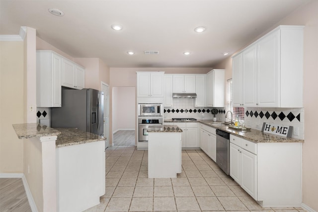 kitchen with white cabinets, stainless steel appliances, visible vents, a sink, and decorative backsplash