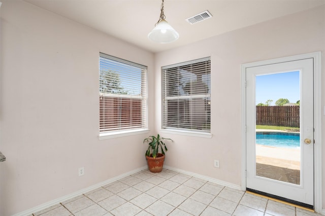 interior space with baseboards, visible vents, light tile patterned floors, and a healthy amount of sunlight