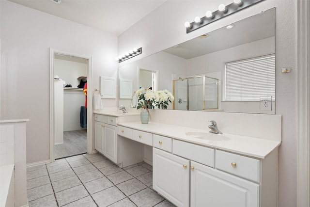 full bathroom with a spacious closet, tile patterned floors, double vanity, a sink, and a stall shower
