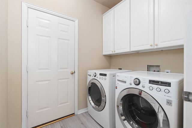 clothes washing area featuring cabinet space, independent washer and dryer, light wood-style flooring, and baseboards