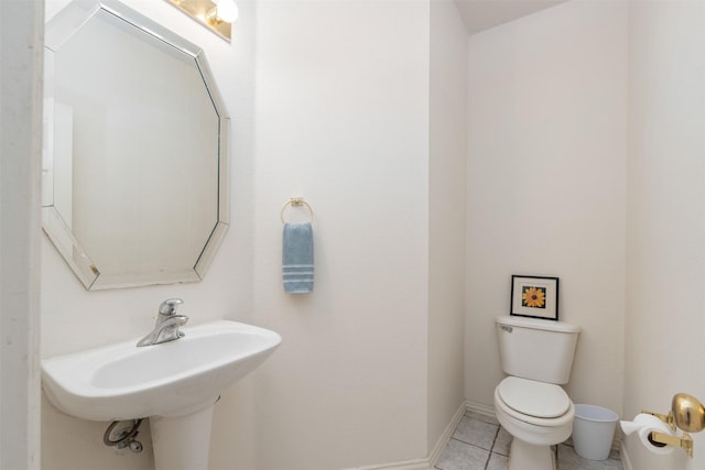 bathroom featuring tile patterned flooring, toilet, baseboards, and a sink