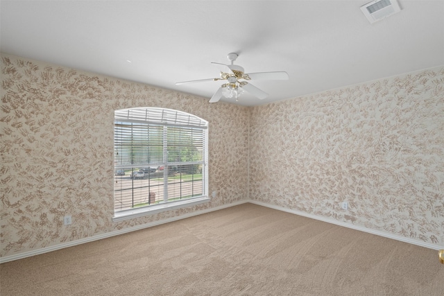 spare room with a ceiling fan, visible vents, carpet flooring, and a healthy amount of sunlight