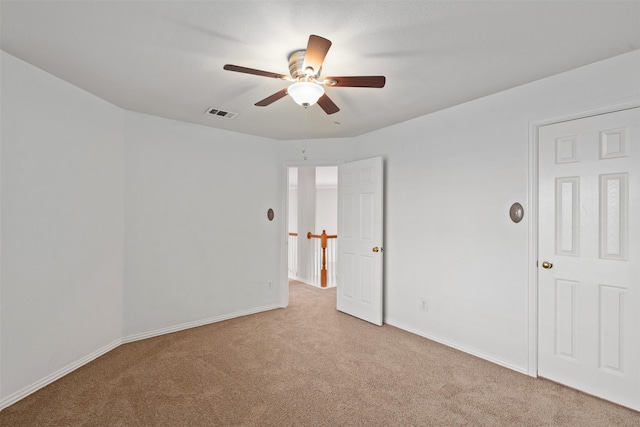 carpeted spare room featuring baseboards, a ceiling fan, and visible vents
