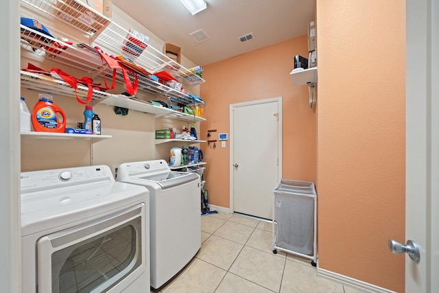 laundry area featuring washer and clothes dryer, light tile patterned flooring, baseboards, visible vents, and laundry area