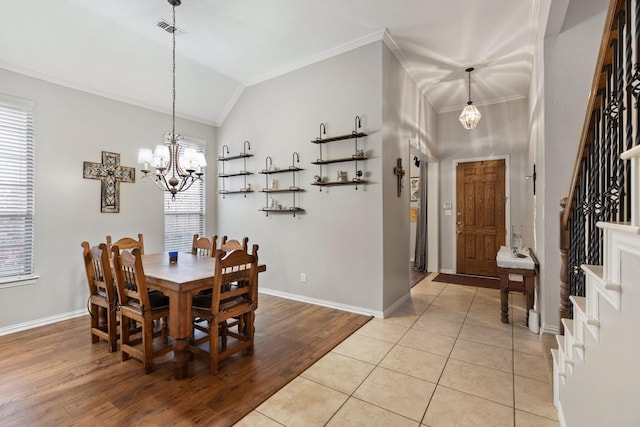 dining room featuring lofted ceiling, visible vents, ornamental molding, baseboards, and a chandelier