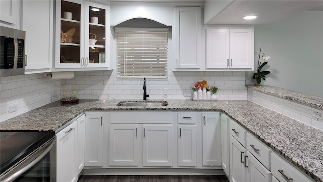 2904 Chestnut Ave, Fort Worth, TX 76106 - kitchen with white cabinets, a sink, stainless steel microwave, tasteful backsplash, and glass insert cabinets
