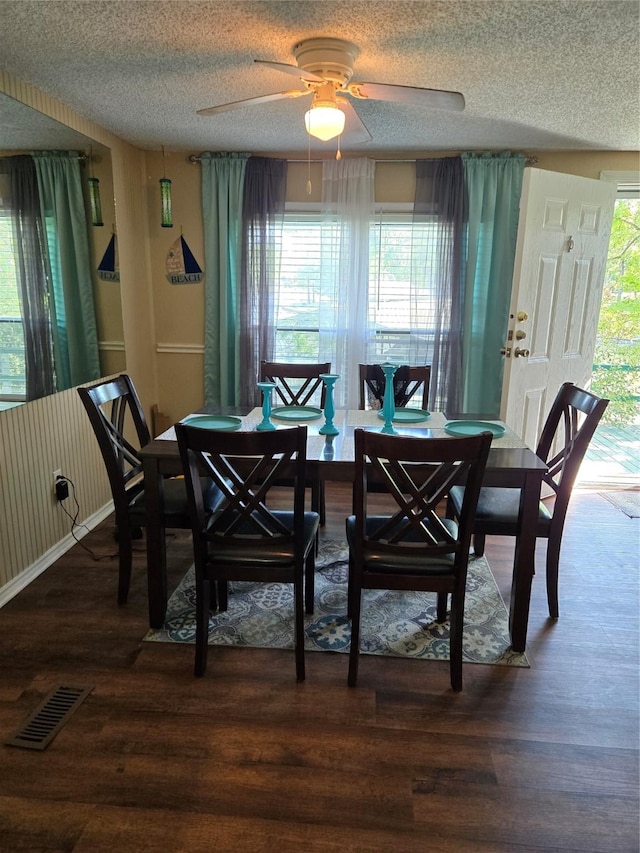 dining area with a ceiling fan, wood finished floors, a textured ceiling, baseboards, and visible vents