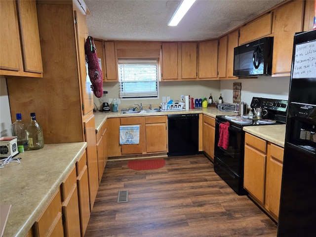 kitchen with a sink, visible vents, light countertops, dark wood-type flooring, and black appliances