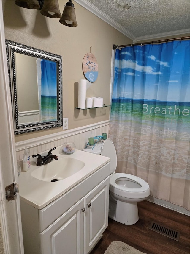 full bathroom with a wainscoted wall, visible vents, wood finished floors, crown molding, and vanity