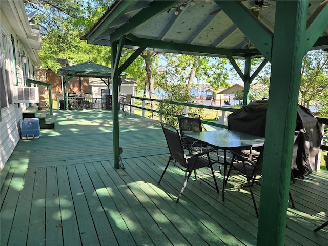 wooden terrace featuring outdoor dining area and a gazebo