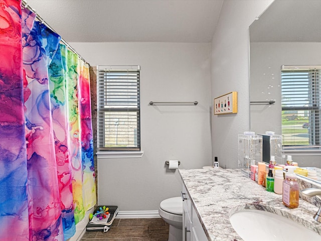 bathroom with a healthy amount of sunlight, vanity, baseboards, and toilet