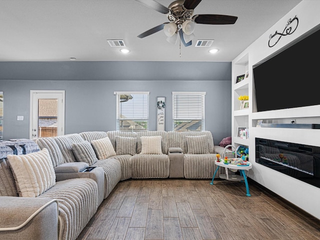 living area with a ceiling fan, wood finished floors, visible vents, and plenty of natural light
