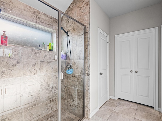 bathroom with a shower stall, a closet, tile patterned floors, and baseboards