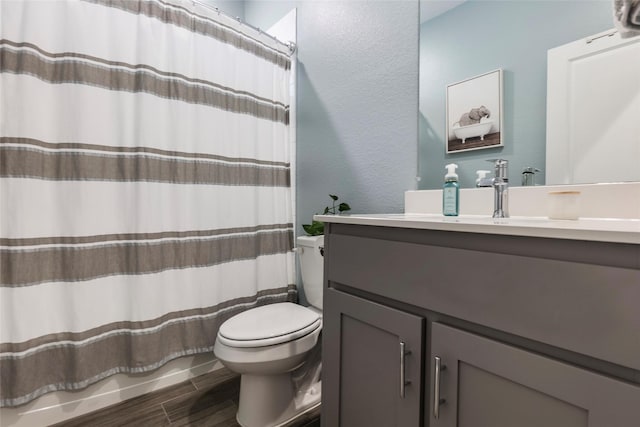 bathroom featuring wood finished floors, vanity, shower / bath combination with curtain, a textured wall, and toilet