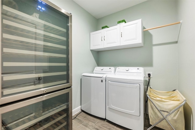 laundry area with wood tiled floor, beverage cooler, cabinet space, baseboards, and independent washer and dryer