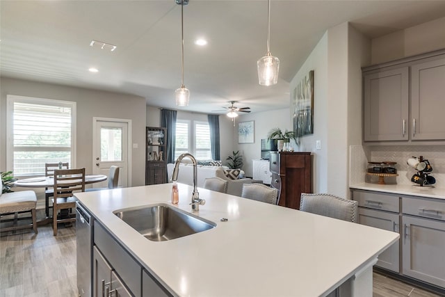 kitchen featuring light countertops, a sink, dishwasher, and gray cabinets