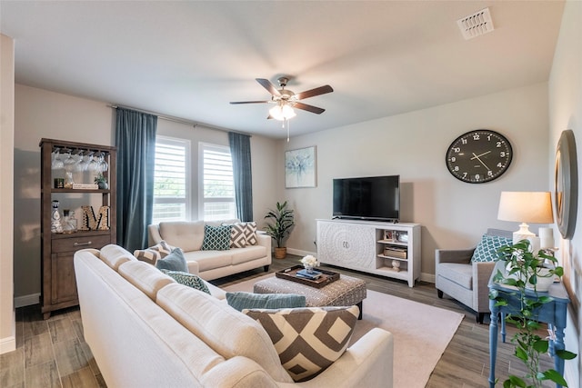 living area featuring light wood-style flooring, visible vents, a ceiling fan, and baseboards