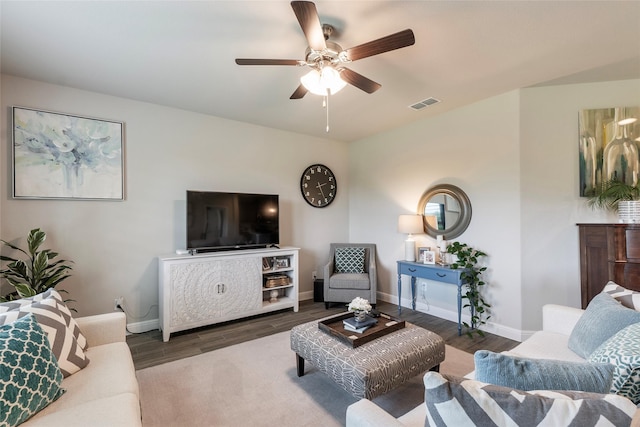living area featuring wood finished floors, visible vents, baseboards, and ceiling fan