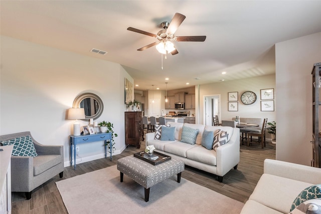 living area with recessed lighting, visible vents, a ceiling fan, dark wood-type flooring, and baseboards