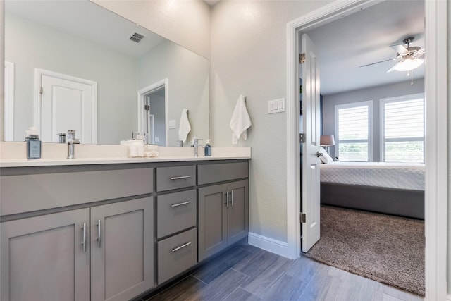full bathroom featuring double vanity, wood finished floors, visible vents, a ceiling fan, and connected bathroom