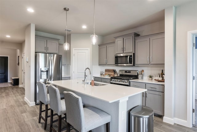 kitchen with gray cabinets, baseboards, stainless steel appliances, and a sink