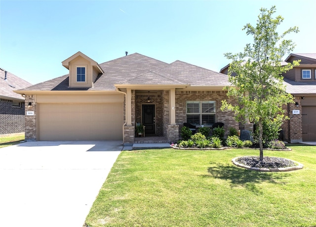 view of front of house featuring brick siding, an attached garage, a front yard, and driveway