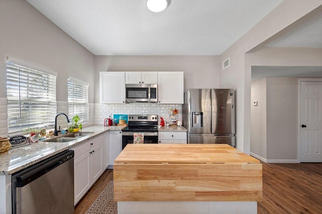 kitchen with stainless steel appliances, visible vents, a sink, butcher block countertops, and dark wood-style flooring