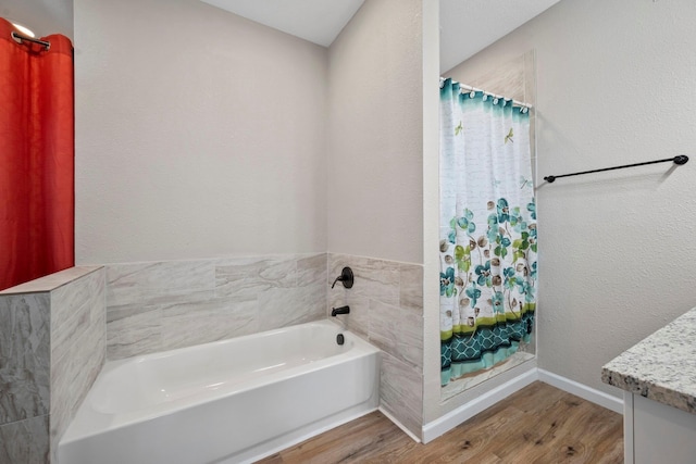 full bath with wood finished floors, vanity, a shower with curtain, baseboards, and a garden tub