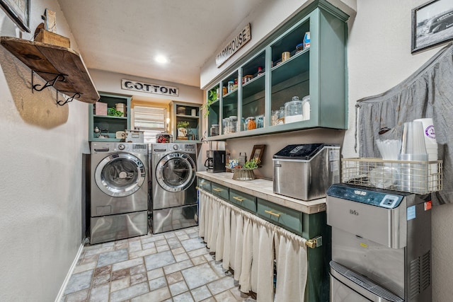 clothes washing area with baseboards, stone finish floor, washer and clothes dryer, and laundry area