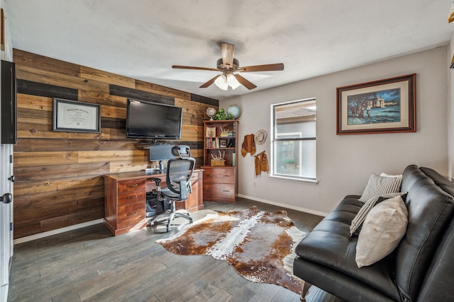 home office featuring wood finished floors, wooden walls, baseboards, and ceiling fan