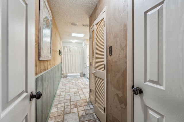 bathroom featuring visible vents, a textured ceiling, and stone finish flooring