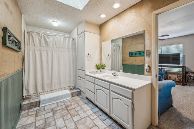 full bathroom featuring ceiling fan, a shower with shower curtain, vanity, and a textured ceiling