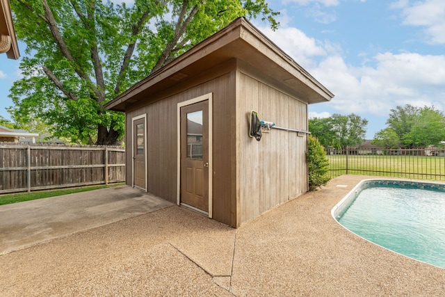 view of outbuilding with fence, a fenced in pool, and an outbuilding