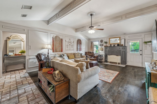 living room with a decorative wall, wood finished floors, lofted ceiling with beams, ceiling fan, and visible vents