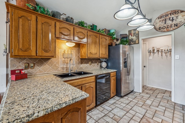 kitchen featuring brown cabinetry, dishwasher, a sink, and stainless steel fridge